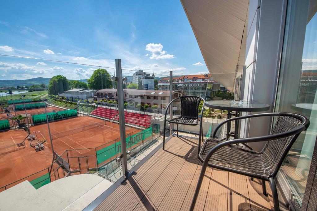un balcón con 2 sillas y una pista de tenis en AQUA SPORT*** en Púchov