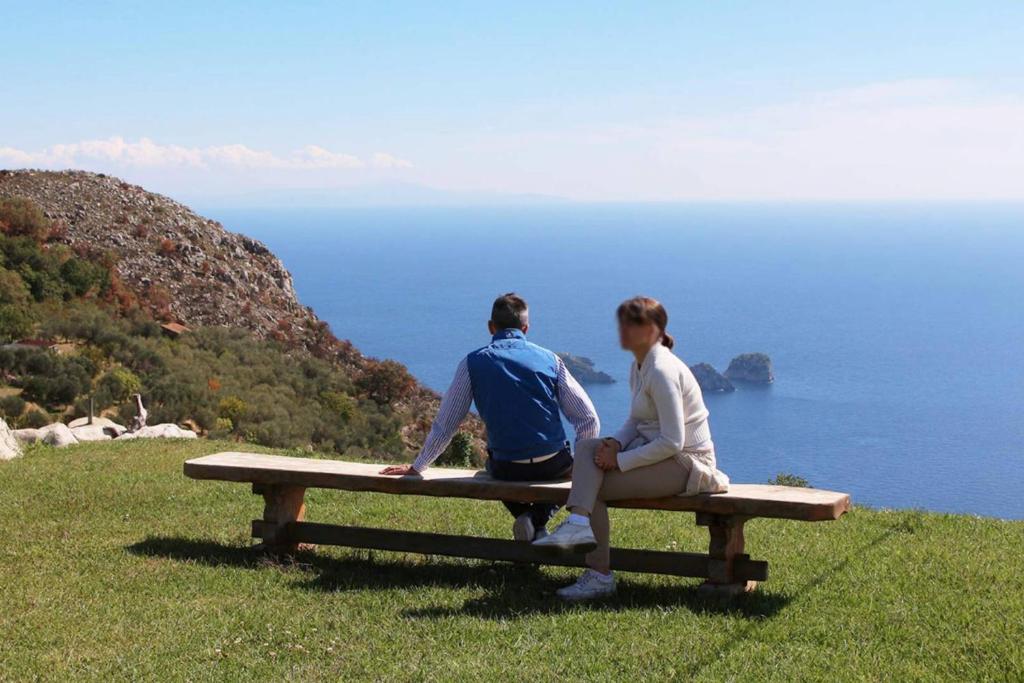 Un uomo e una donna seduti su una panchina che si affaccia sull'oceano di The Sea Farmhouse a Sorrento