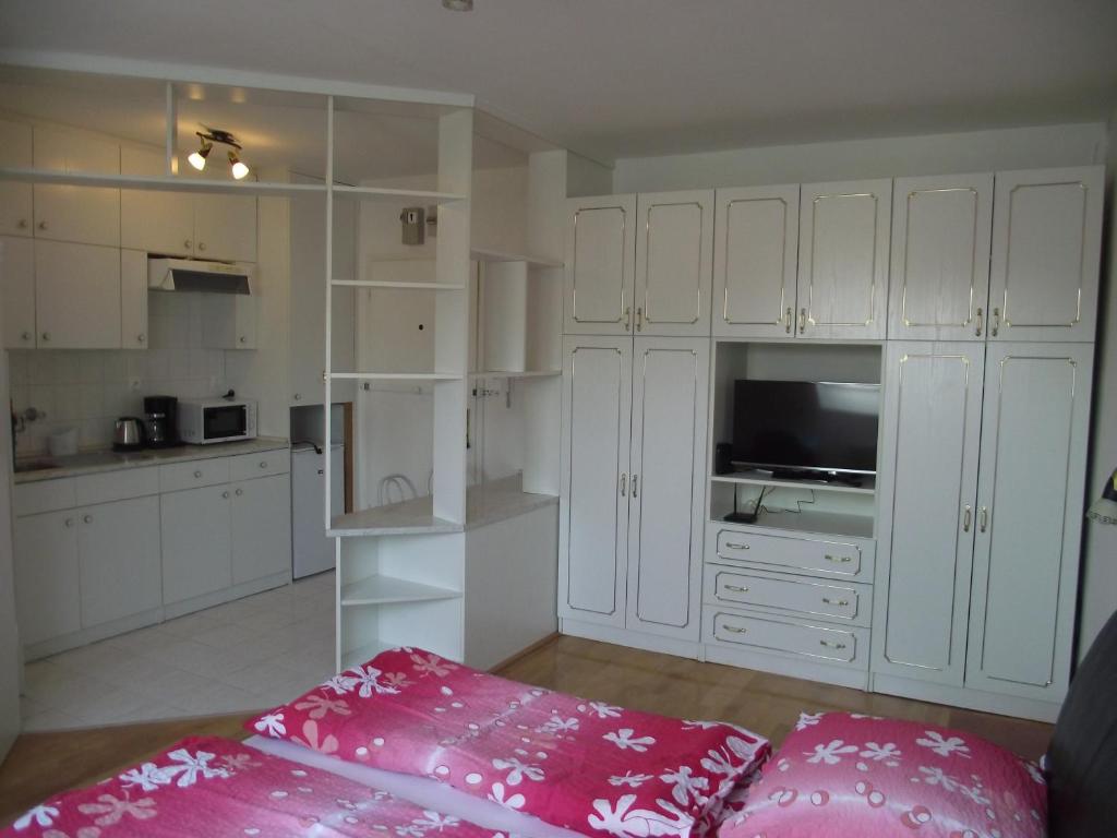 a white kitchen with white cabinets and a pink pillow at Apartman Kaszás City in Mosonmagyaróvár