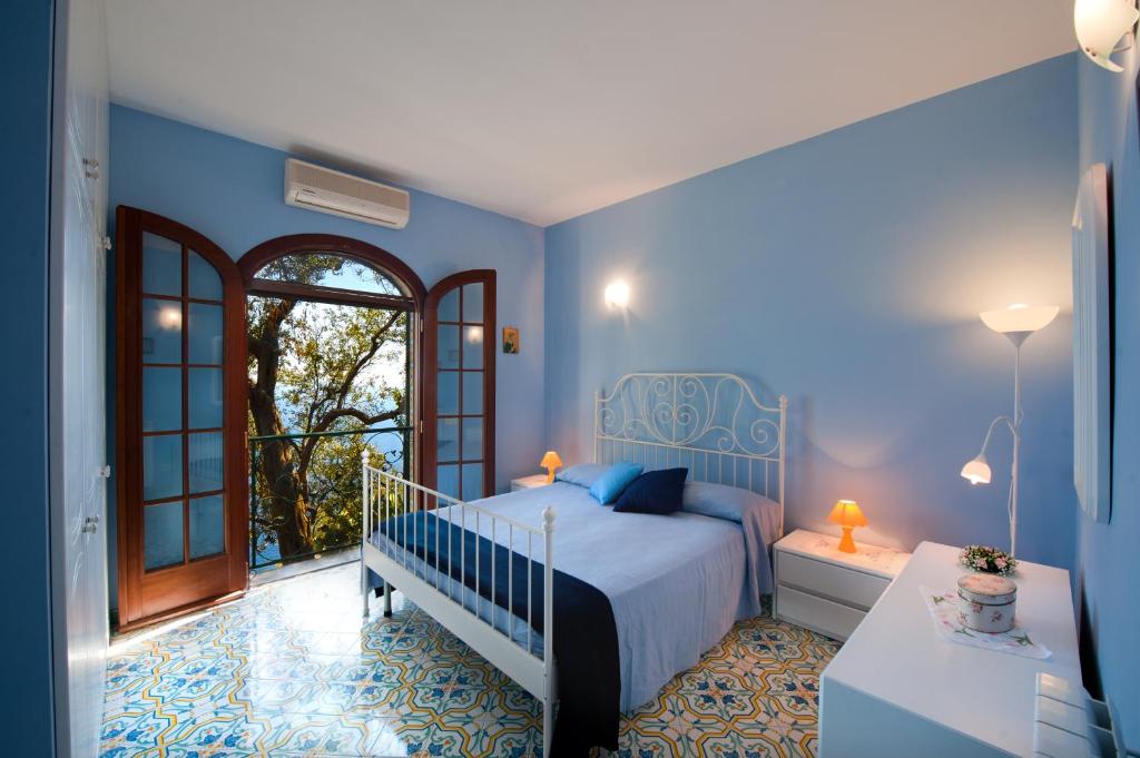 ein blaues Schlafzimmer mit einem Bett und einem Balkon in der Unterkunft Casa Marea in Conca dei Marini