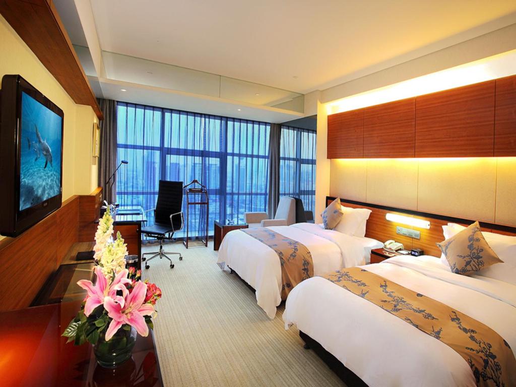 天津市にあるグランド ビュー ホテル ティアンジンのベッド2台とテレビが備わるホテルルームです。