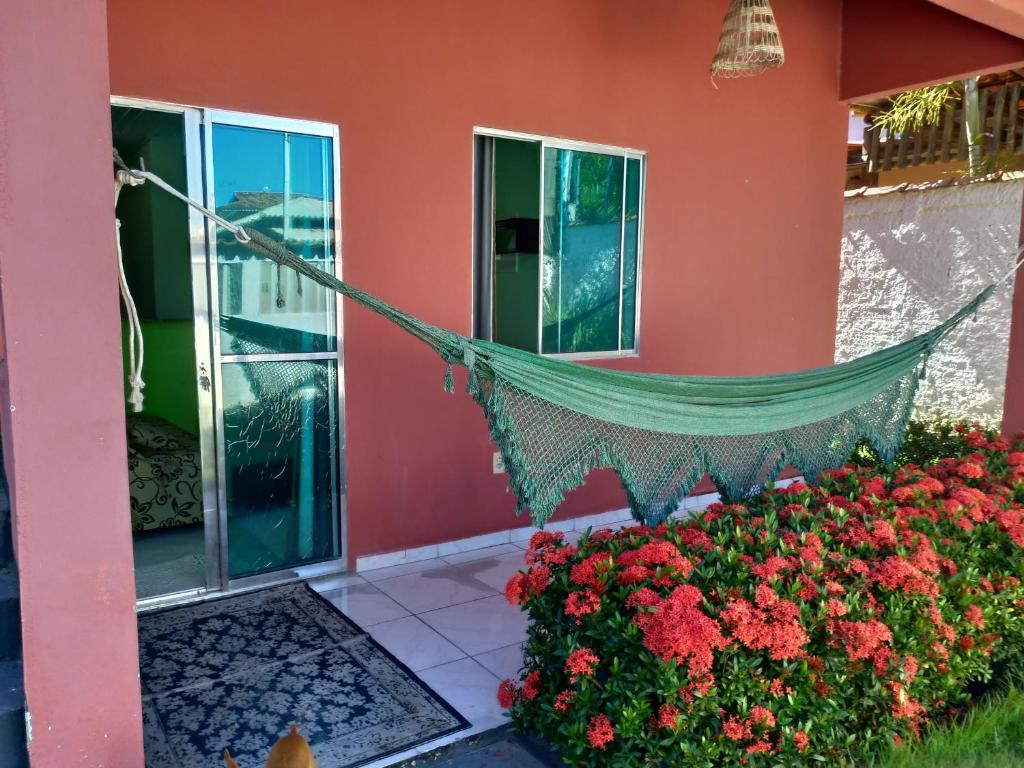 a hammock hanging outside of a house with flowers at Kitnet Coroa Vermelha in Santa Cruz Cabrália