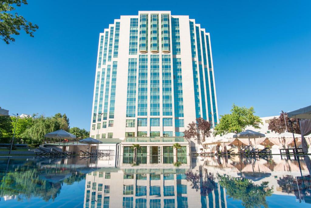 a tall white building with its reflection in the water at City Palace Hotel Tashkent in Tashkent