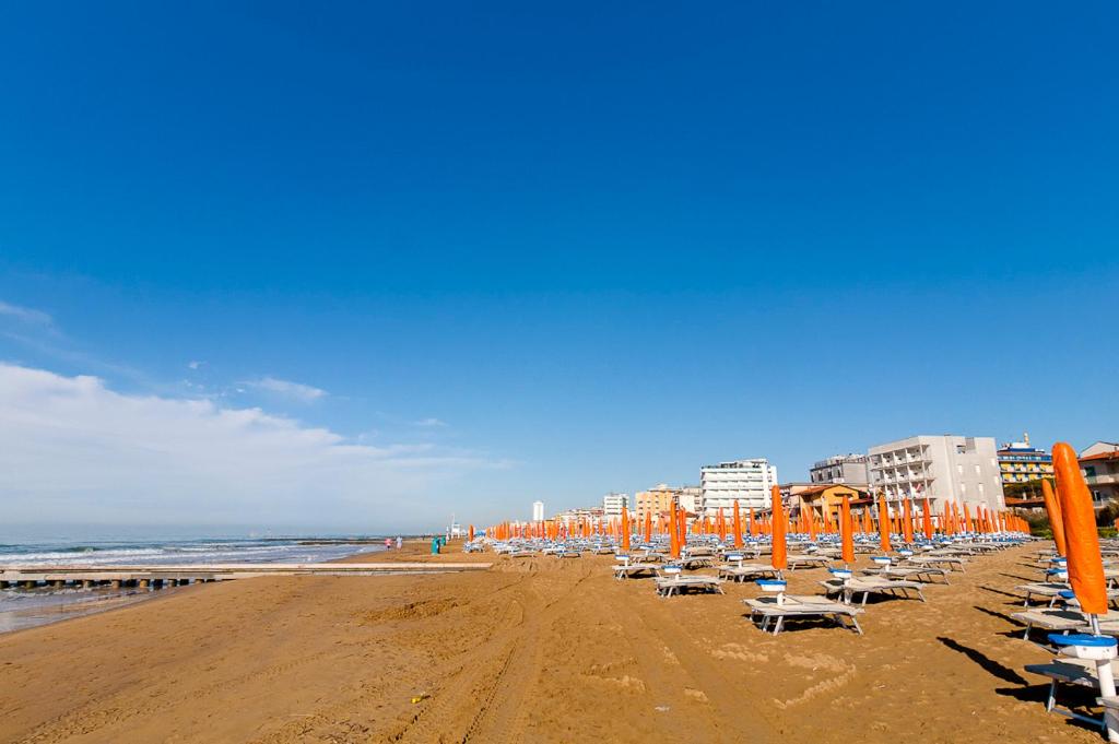 einen Strand mit Liegestühlen und Sonnenschirmen und dem Meer in der Unterkunft Hotel Astromare in Lido di Jesolo