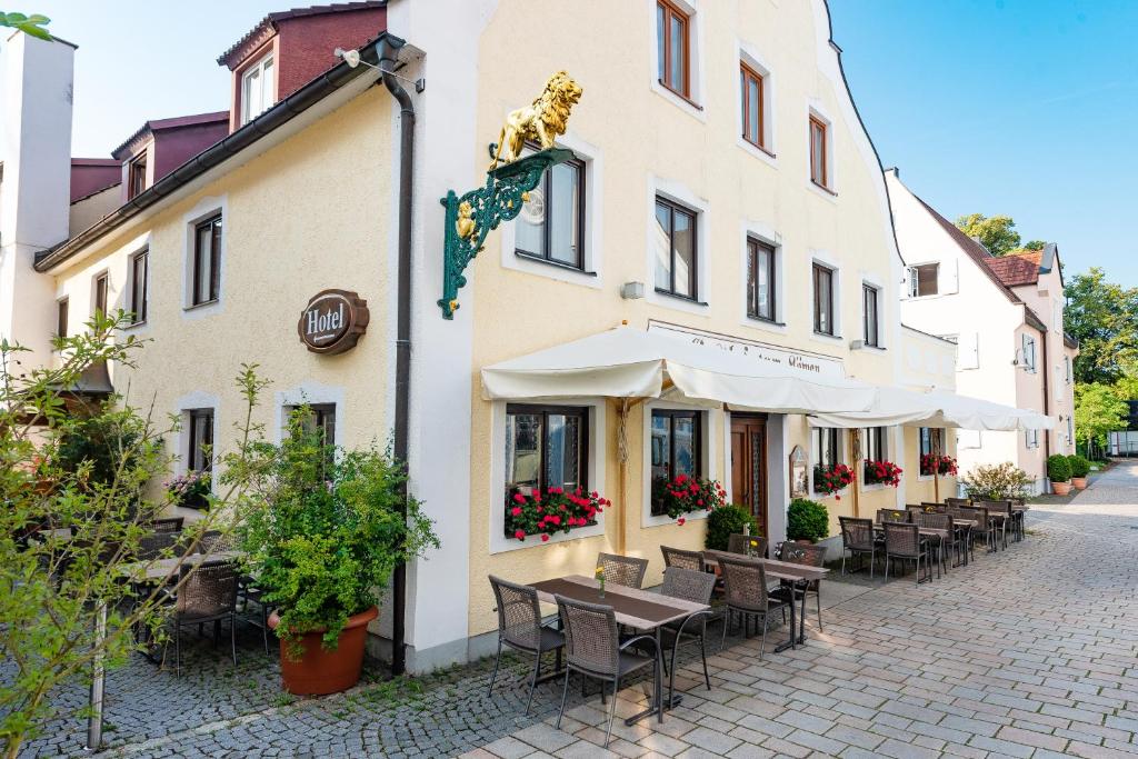 un edificio con mesas y sillas fuera de él en Hotel zum Löwen en Weißenhorn