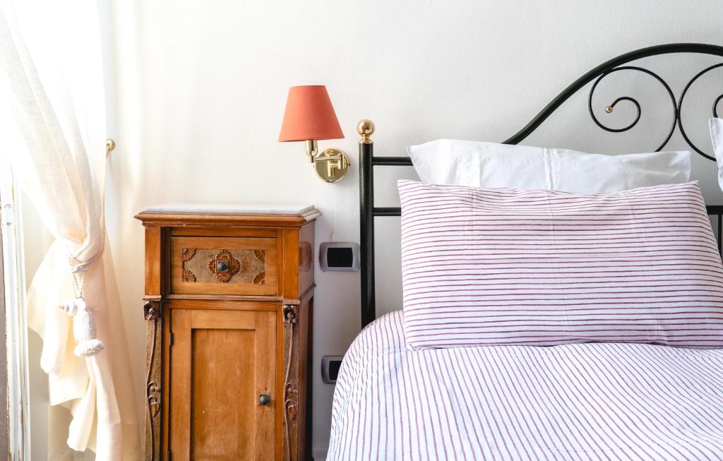 een bed met een gestreept kussen en een nachtkastje bij Appartamento Calarossa in Siracusa