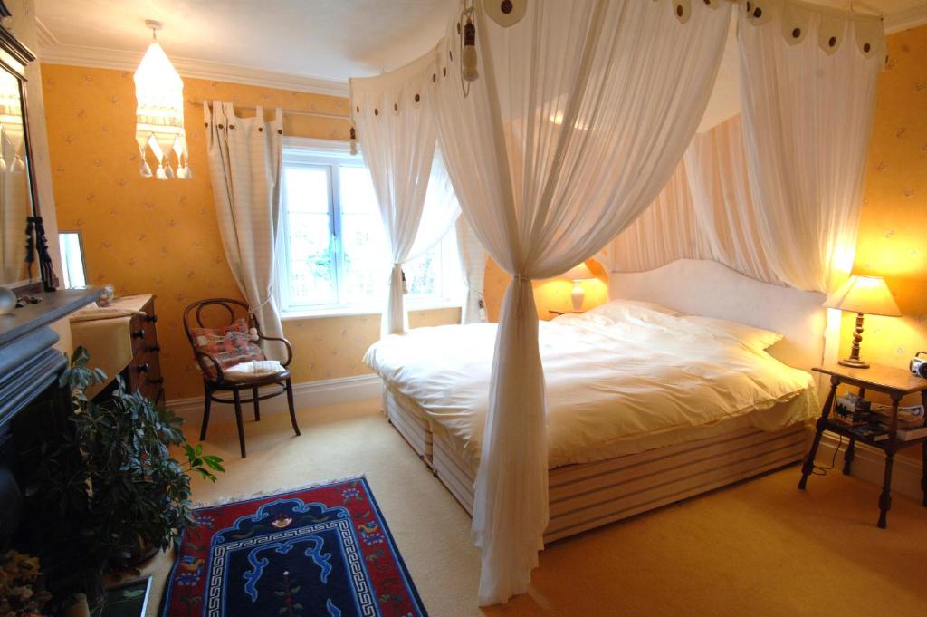 - une chambre avec un lit à baldaquin et des rideaux dans l'établissement Seawall, 30A Burlington Road, à Swanage