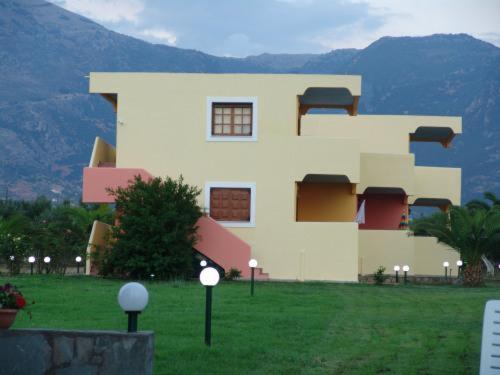 a large building in a field with mountains in the background at Terpsichore Apartments in Kyparissia