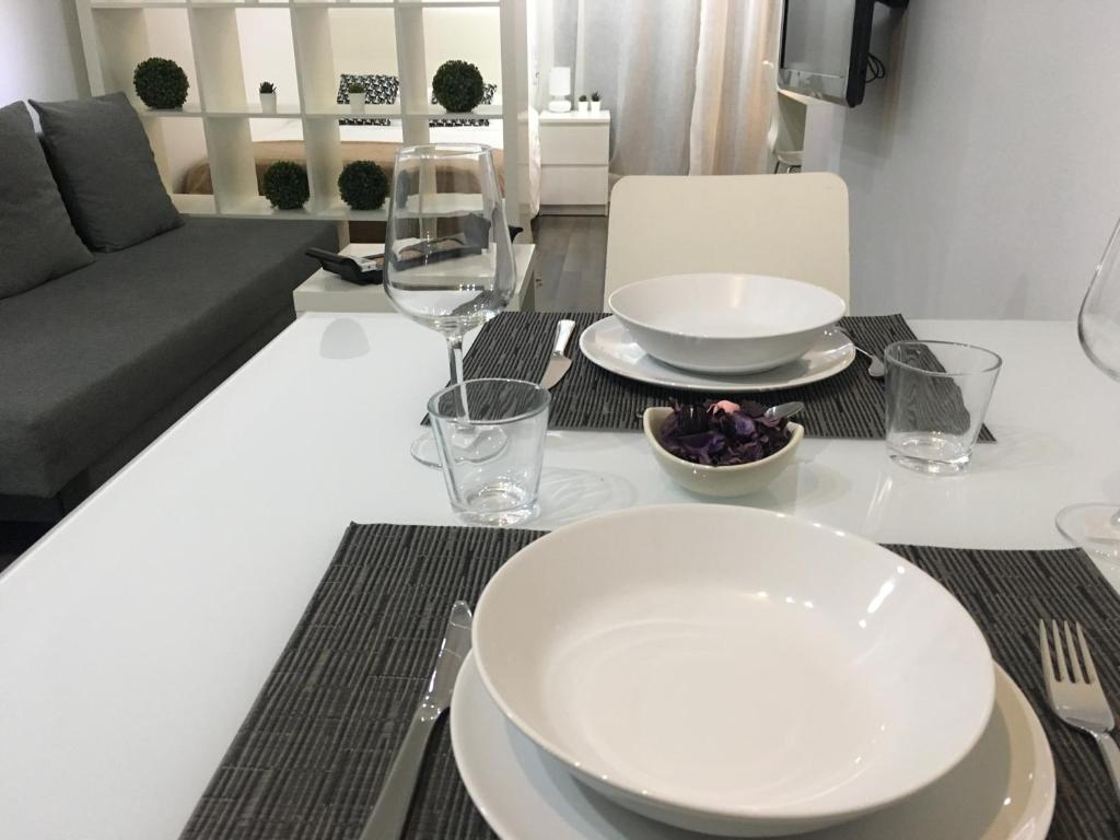a dining room table with plates and glasses and a couch at Zerka Centro in Valencia
