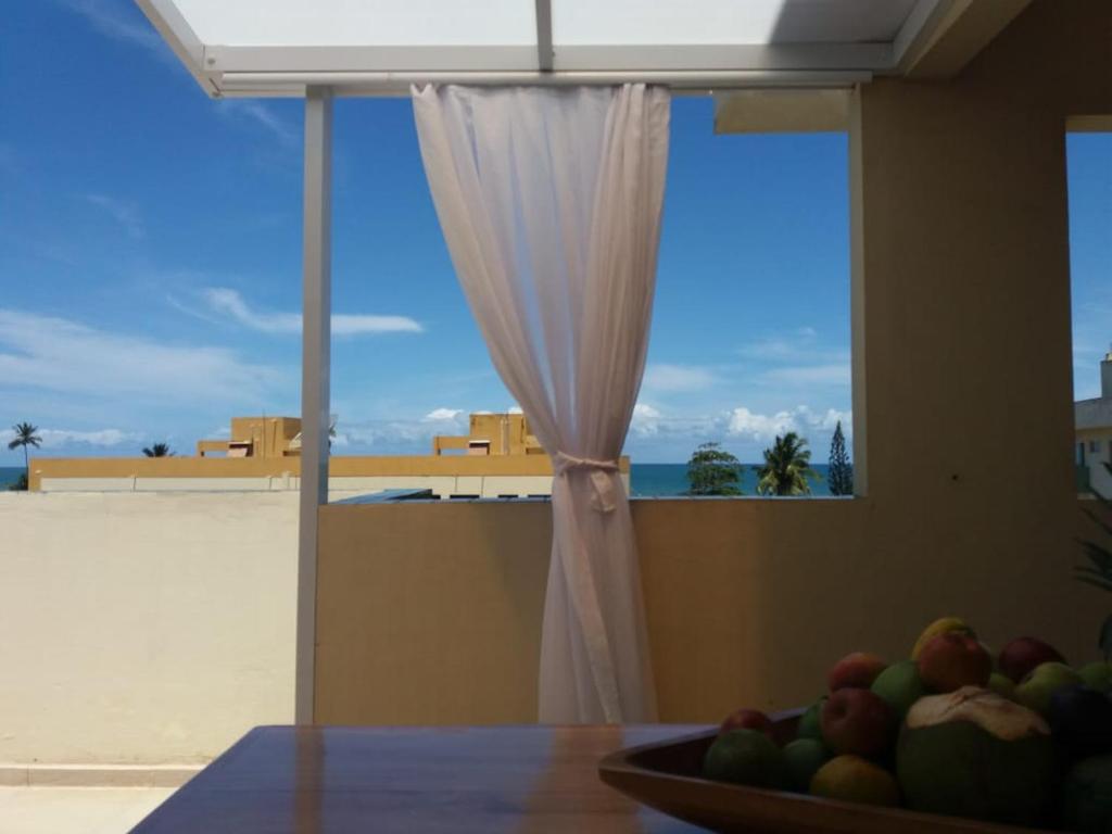 a bowl of fruit on a table in front of a window at Cobertura Duplex Na Praia Dos Milionários in Ilhéus