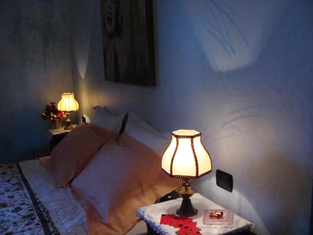 um quarto com uma cama e uma mesa com um candeeiro em La Coccinella B&B em Boves