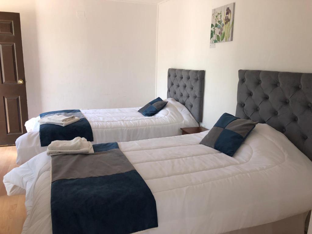 two beds in a hotel room with white and blue at Hotel Cecil in Vallenar