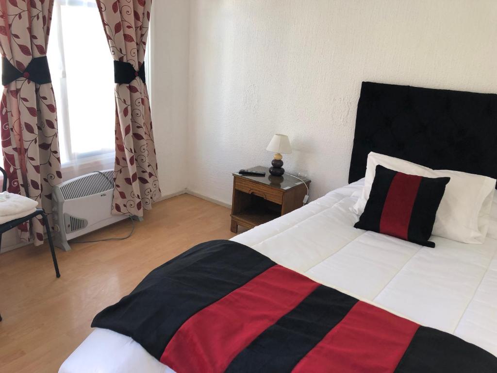 a bedroom with a bed with a black and red blanket at Hotel Cecil in Vallenar