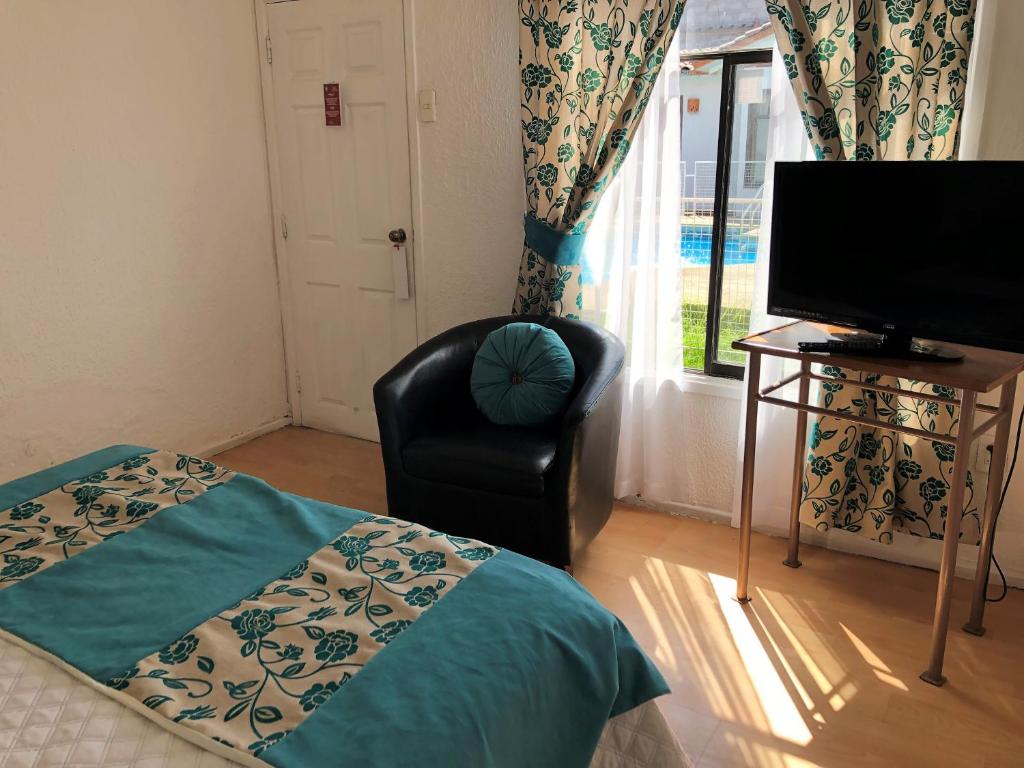 a bedroom with a bed and a chair and a television at Hotel Cecil in Vallenar