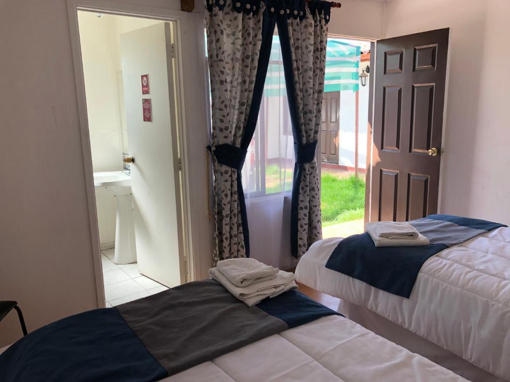 two beds in a room with a door and a window at Hotel Cecil in Vallenar