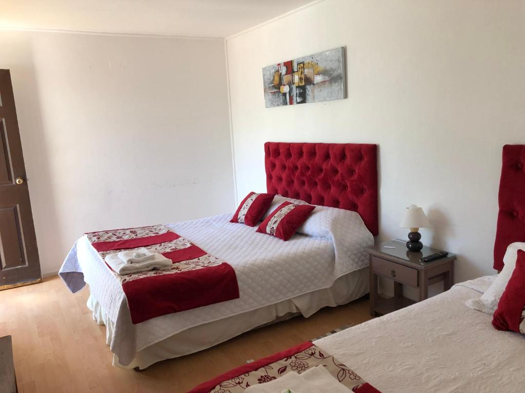 a bedroom with two beds and a red headboard at Hotel Cecil in Vallenar