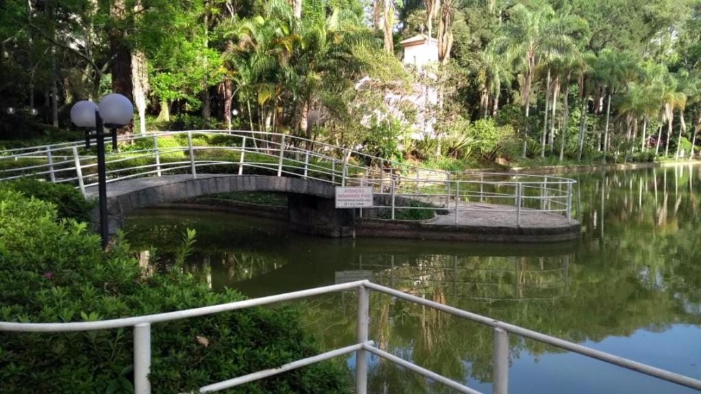 a bridge over a river in a park at Apts no Condominio Quisisana in Poços de Caldas