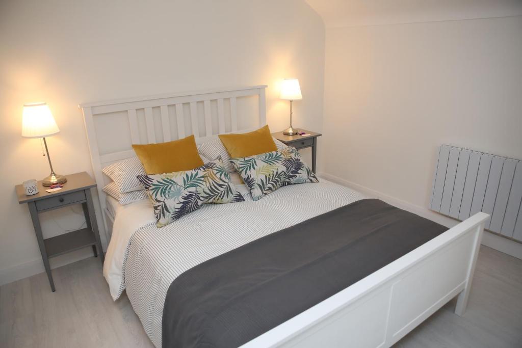 um quarto com uma grande cama branca com almofadas em East Bridge Apartments em Enniskillen