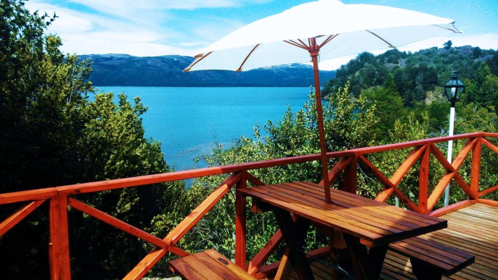a wooden bench with an umbrella on a wooden deck at Cabañas Aucaman in Villa Pehuenia