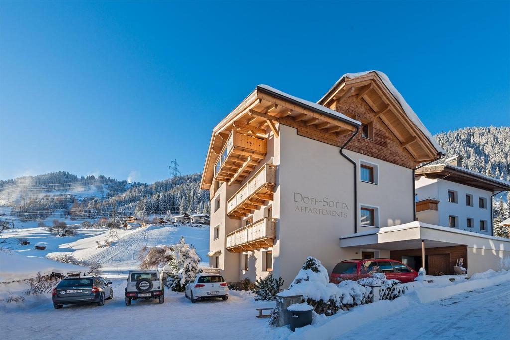 a large building with cars parked in the snow at Doff-Sotta Appartements in Sankt Anton am Arlberg