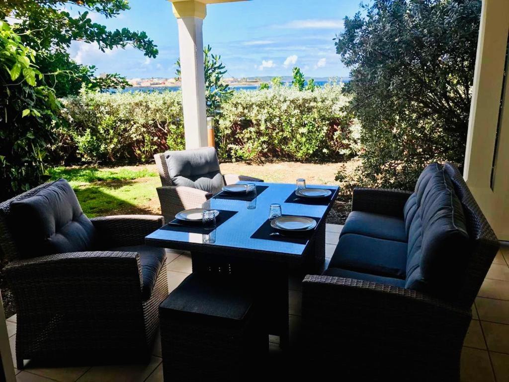 a table and chairs on a patio with a view of the ocean at Appartement Au Bord de Mer in Le Moule