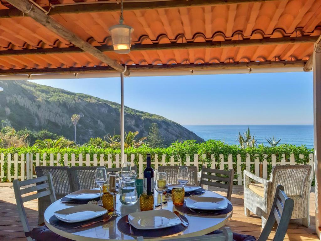 a table with glasses and a bottle of wine on a patio at The Beachfront Casa da Rampa in Sintra