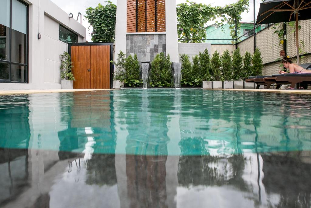 a swimming pool in front of a house at Amenity Apartel Samui in Lamai