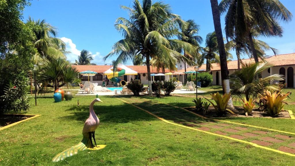 a bird standing in the grass in front of a house at Hotel Praia do Conde in Conde