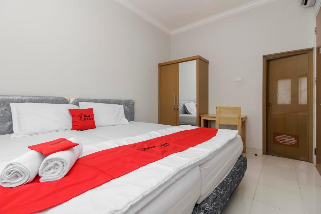Una cama grande con toallas rojas y blancas. en RedDoorz near Central Park Mall, en Yakarta