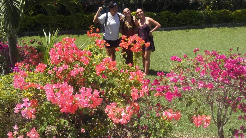trzy osoby stojące w ogrodzie z kwiatami w obiekcie Lorenton Hideaway w mieście Lucea