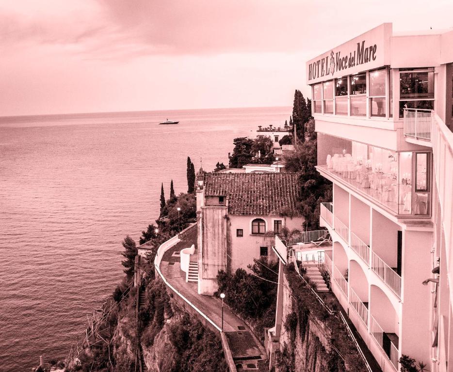 a building on a cliff next to the water at Hotel Voce del Mare in Vietri sul Mare