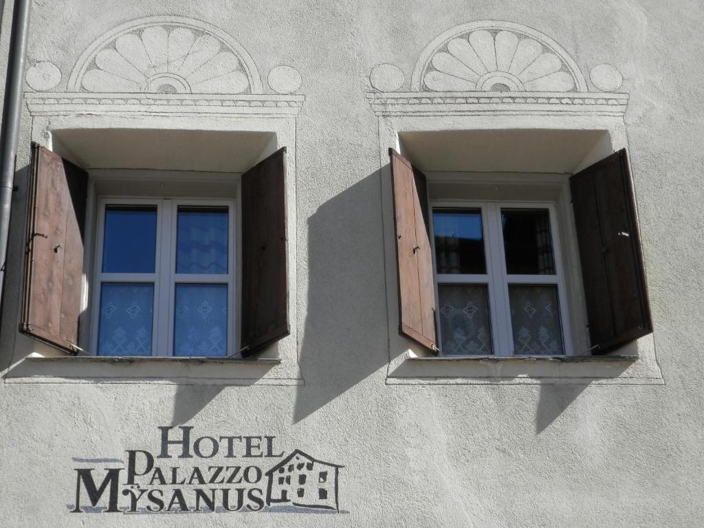 two windows on the side of a building with wooden shutters at Palazzo Mysanus Samedan in Samedan