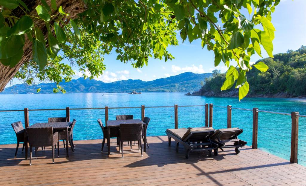a deck with tables and chairs and a view of a lake at Anse Soleil Beachcomber Hotel and Self Catering in Baie Lazare Mahé