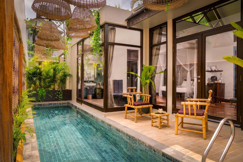 a villa with a swimming pool and two chairs at Heritage Suites Hotel in Siem Reap