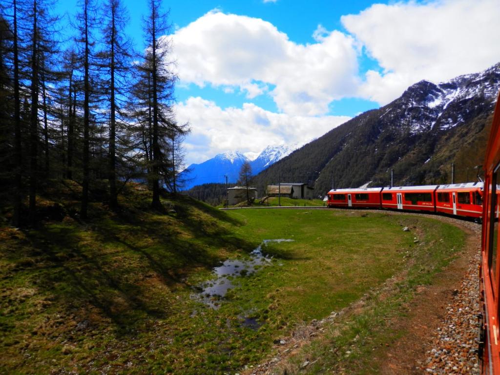 a red train is traveling through the mountains at Palazzo Mysanus Samedan in Samedan