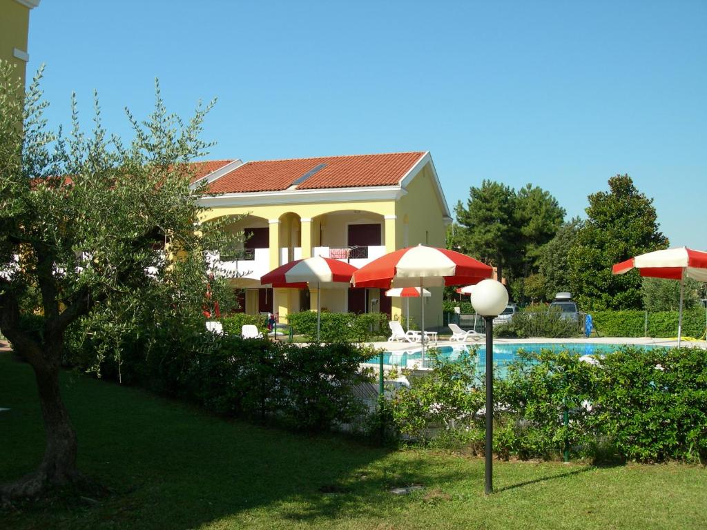 a house and a swimming pool with umbrellas and a house at Villaggio Borgo dell'Ulivo in Bibione