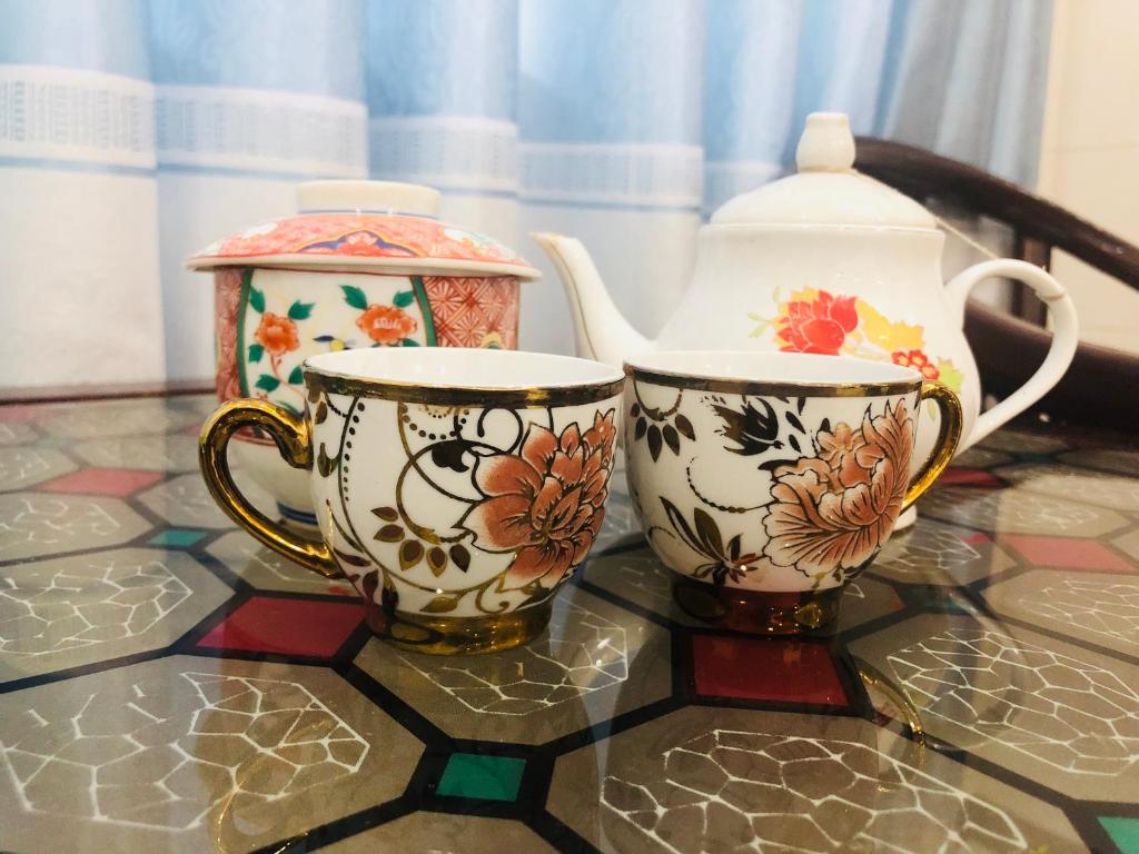 two cups and a tea pot on a glass table at Thien Thanh Hotel in Vĩnh Long