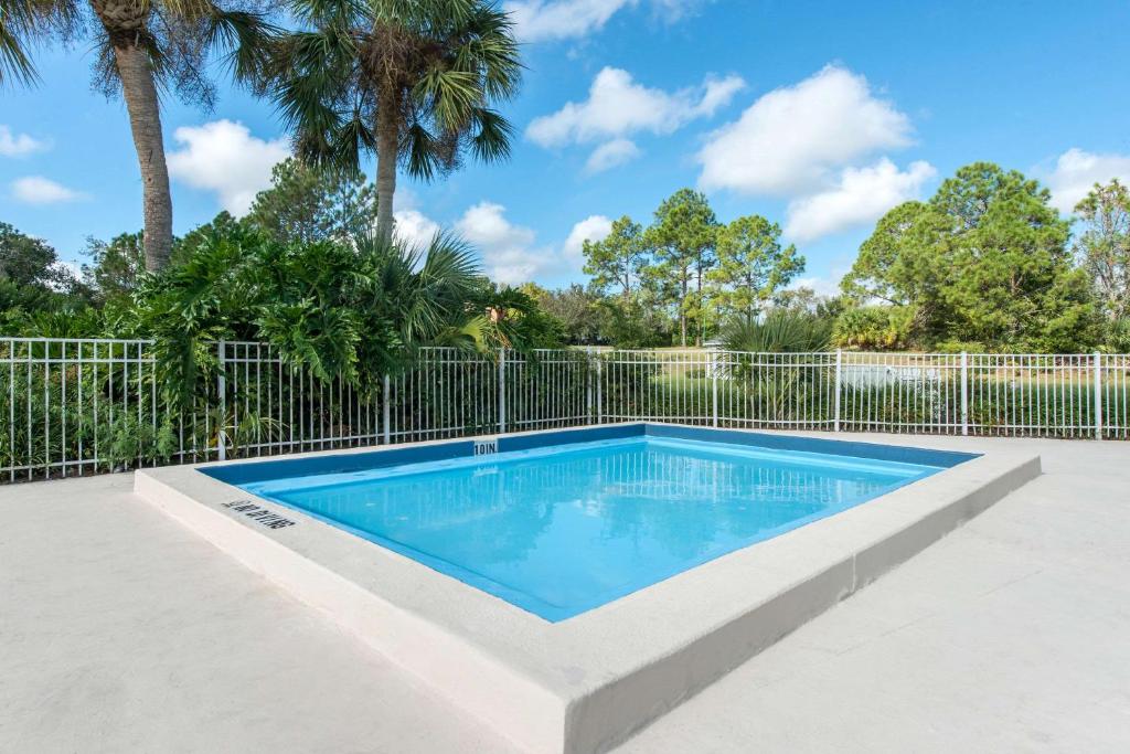 a swimming pool with a fence and palm trees at Quality Inn & Suites Brooksville I-75-Dade City in Ridge Manor