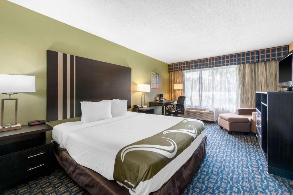 a hotel room with a large bed and a living room at Quality Inn & Suites Brooksville I-75-Dade City in Ridge Manor