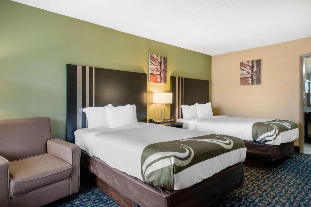 a hotel room with two beds and a chair at Quality Inn & Suites Brooksville I-75-Dade City in Ridge Manor