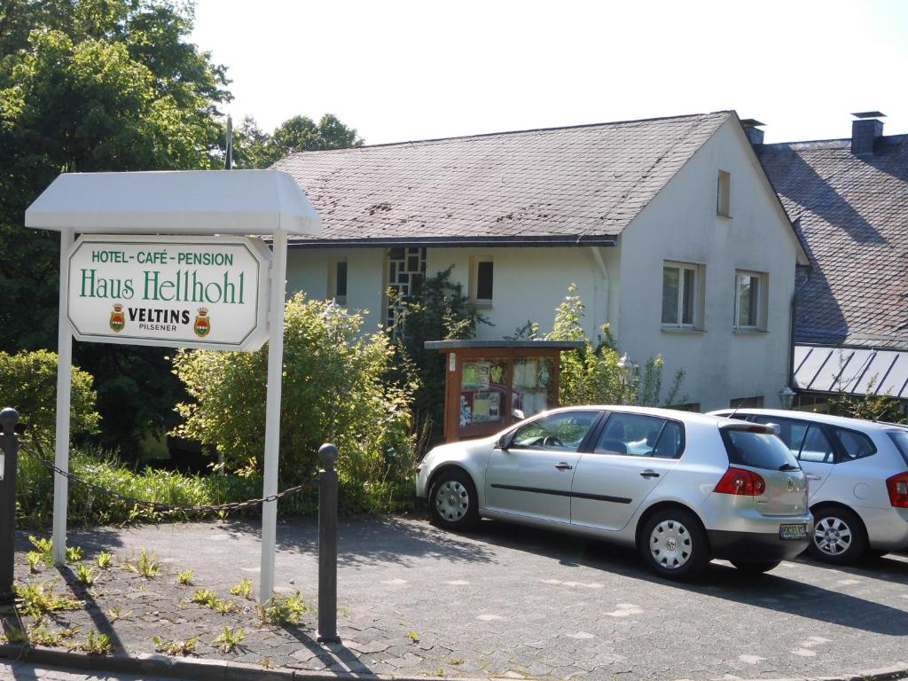 una señal frente a una casa con coches aparcados en Hotel Haus Hellhohl, en Brilon