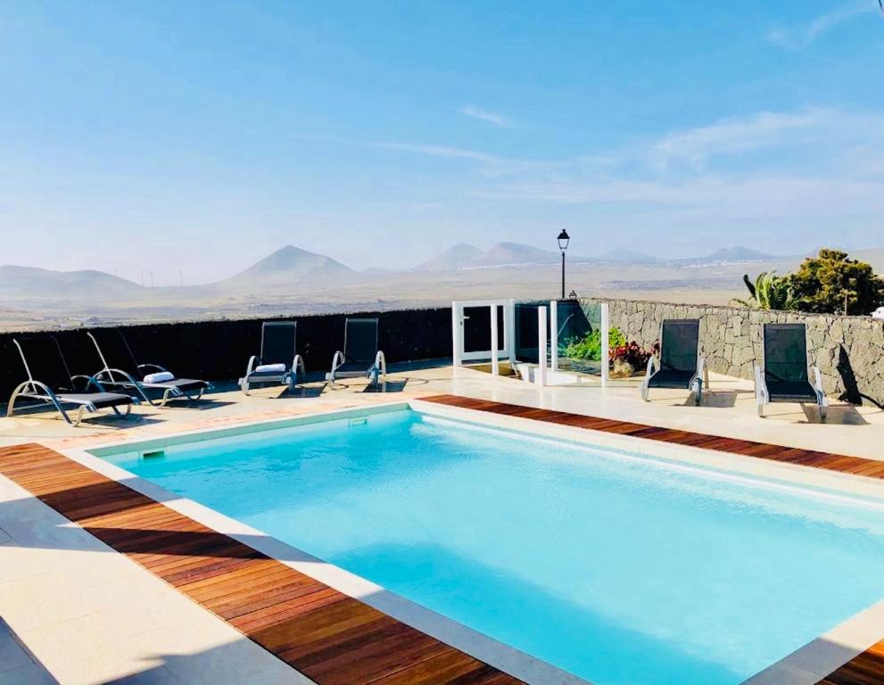 a large swimming pool with chairs at Canaryislandshost l Infinity Views in Nazaret