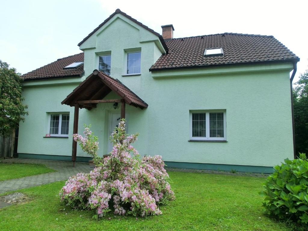 a white house with a flowering bush in front of it at Privát Folprechtovi in Dobšín