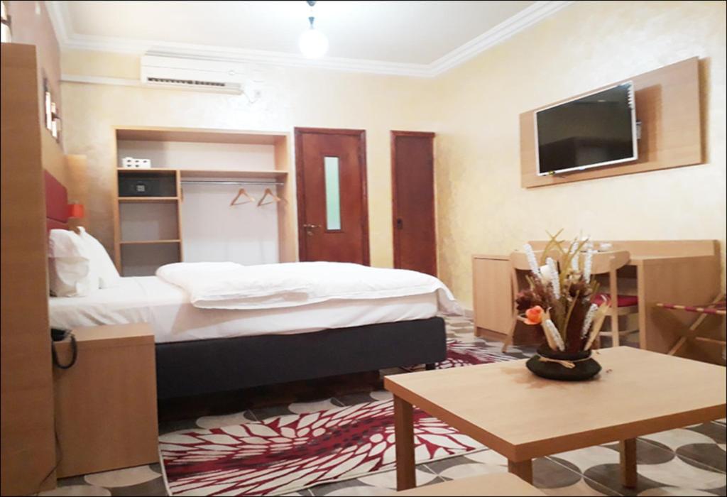 ein Hotelzimmer mit einem Bett und einem TV in der Unterkunft TAKIALT in Adrar