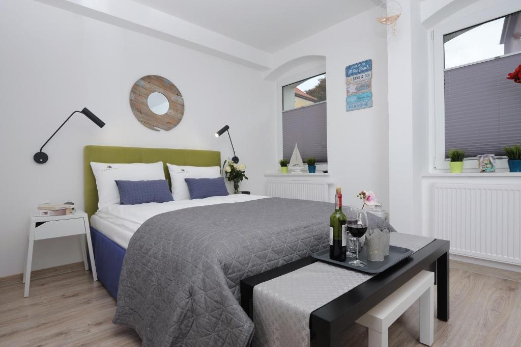 1 dormitorio con 1 cama y 1 mesa con botellas de vino en Apartamenty Via Mare, en Ustka
