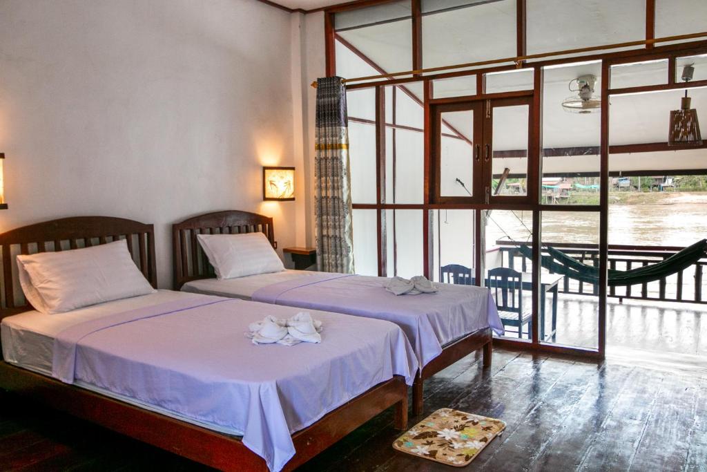 a bedroom with two beds and a large window at Dokchampa Guesthouse in Ban Khon