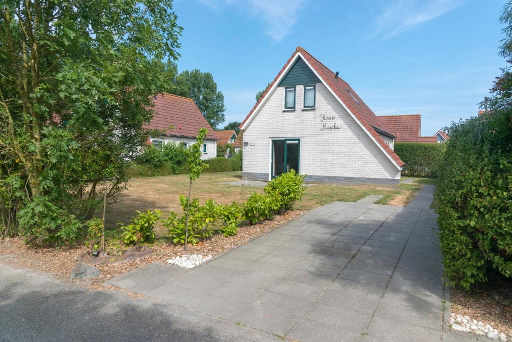 una casa blanca con una entrada delante de ella en Hello Zeeland - Vakantiehuis Zeemeeuw 126, en Breskens