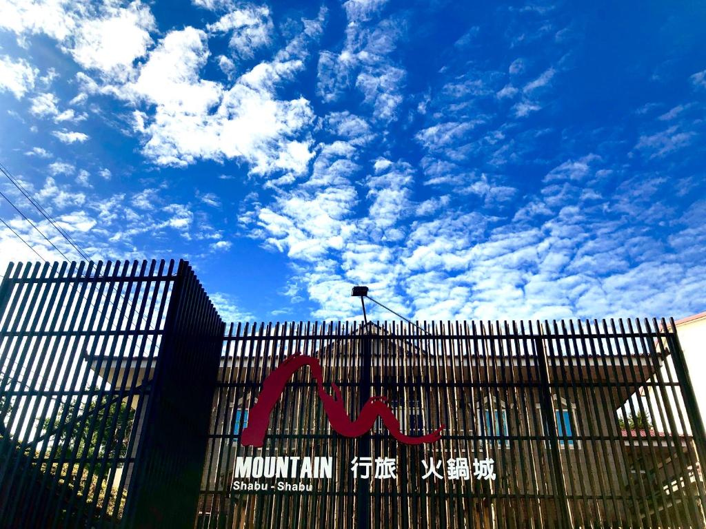 a building with a fence with a blue sky with clouds at MountainTraveler in Renai