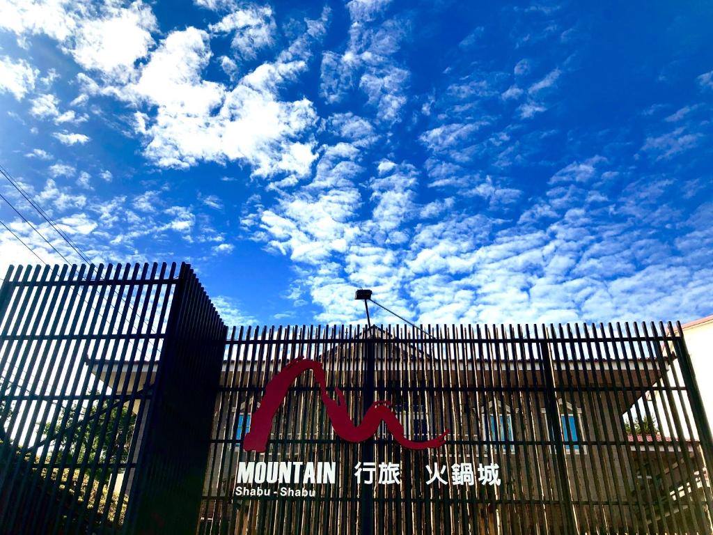 un edificio con una valla con un cielo azul con nubes en MountainTraveler, en Renai