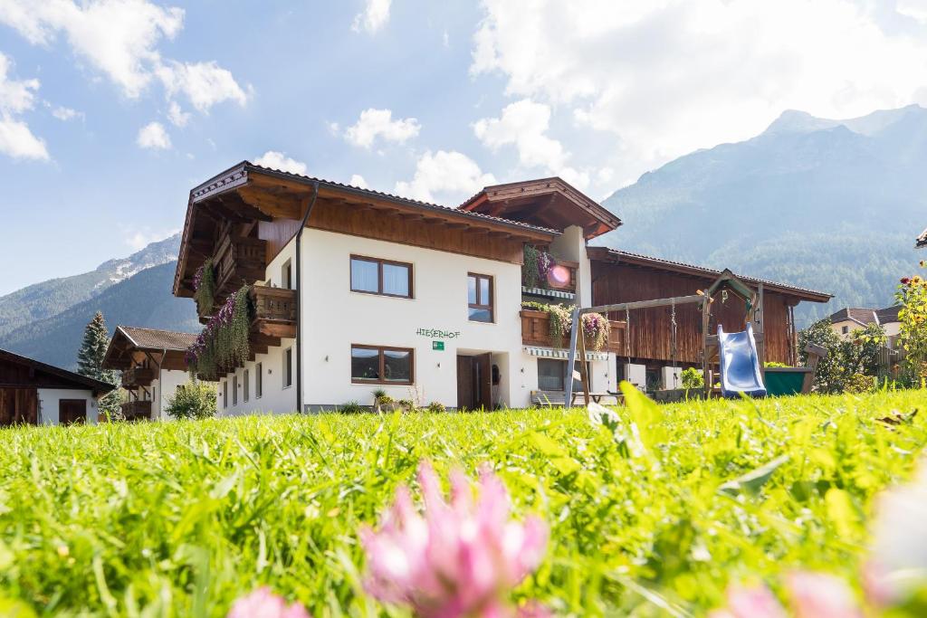 a house in a field with flowers in the foreground at Hieserhof in Neustift im Stubaital